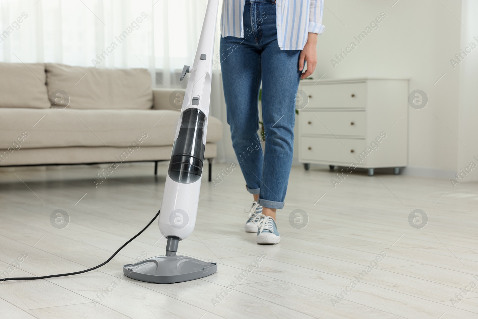 Photo of Woman cleaning floor with steam mop at home, closeup