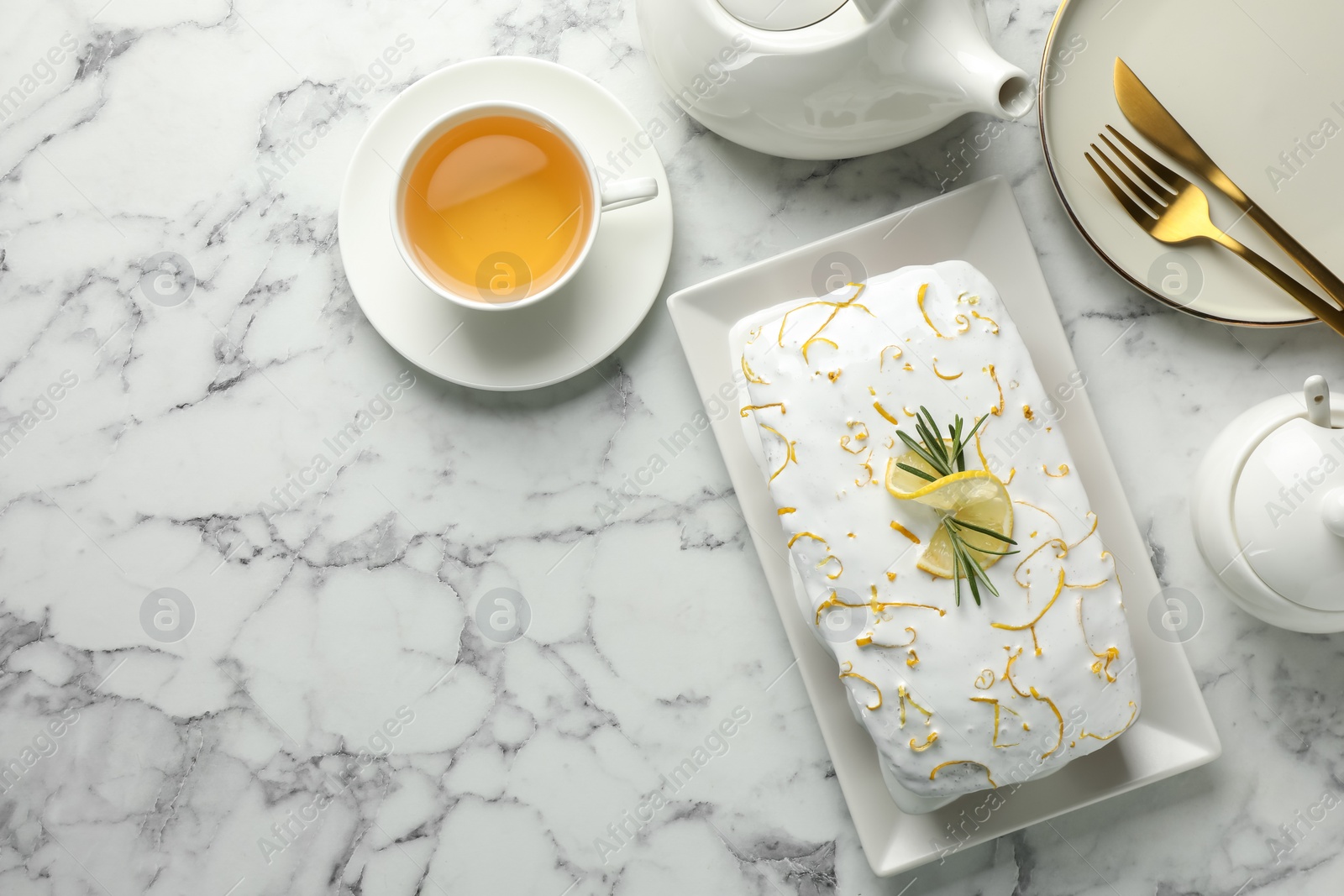 Photo of Tasty lemon cake with glaze served on white marble table, flat lay. Space for text