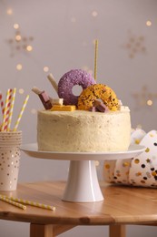 Photo of Delicious cake decorated with sweets and festive items on wooden table