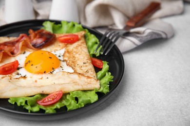 Delicious crepe with egg served on light gray table, closeup. Breton galette