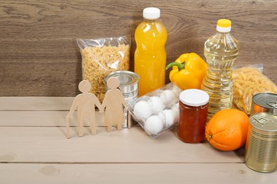 Humanitarian aid for elderly people. Different donation food and figures of senior couple on wooden table