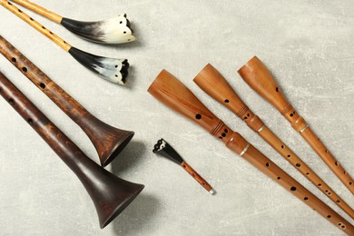 Photo of Vintage zhaleikas and bryolkas on light grey background, flat lay. Woodwind musical instruments