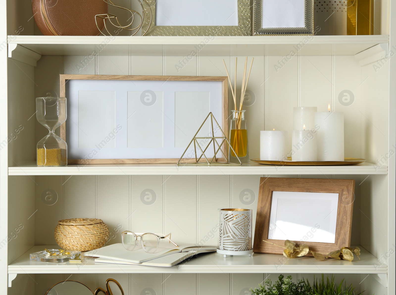 Photo of White shelving unit with photo frames and different decorative elements