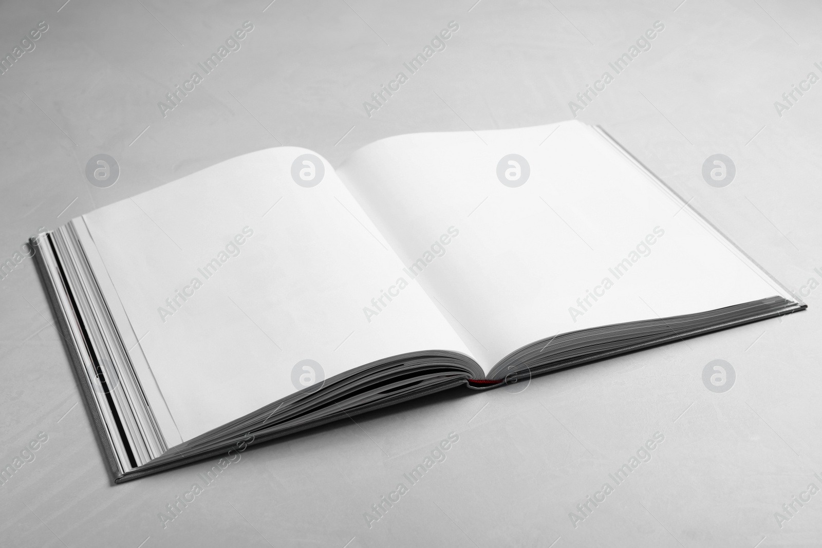 Photo of Open book with hard cover on light grey table