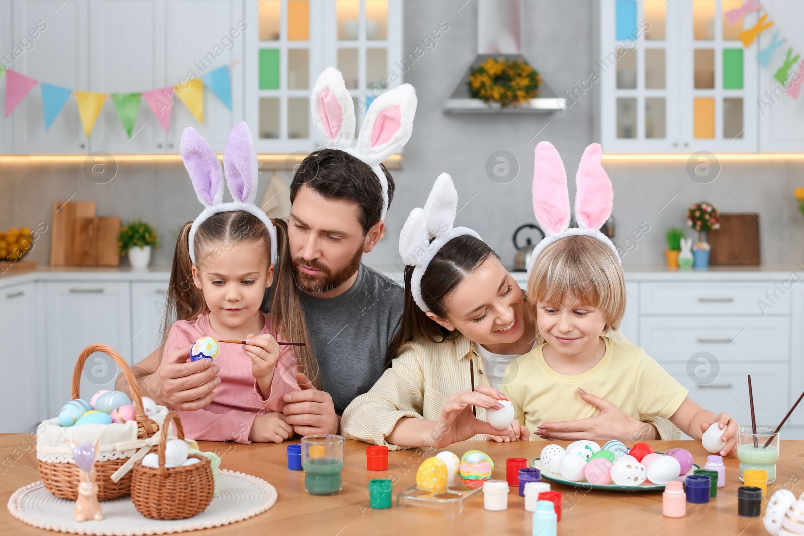 Photo of Happy family painting Easter eggs at table in kitchen