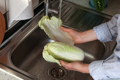 Photo of Woman washing fresh Chinese cabbage in sink, closeup