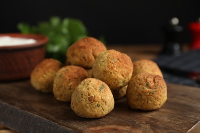 Photo of Delicious falafel balls on wooden board, closeup