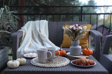Photo of Rest on terrace with rattan furniture. Drink, dessert and autumn decor on table