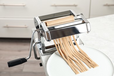 Photo of Preparing soba (buckwheat noodles) with pasta maker machine at table in kitchen