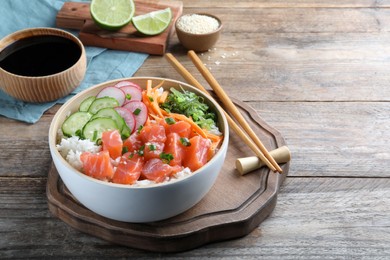 Delicious poke bowl with salmon and vegetables served on wooden table. Space for text