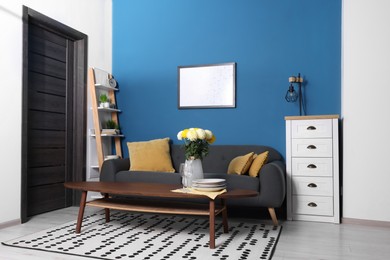 Stylish living room interior with comfortable grey sofa and coffee table