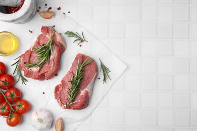 Photo of Fresh raw meat with rosemary, oil, tomatoes and spices on white tiled table, flat lay. Space for text