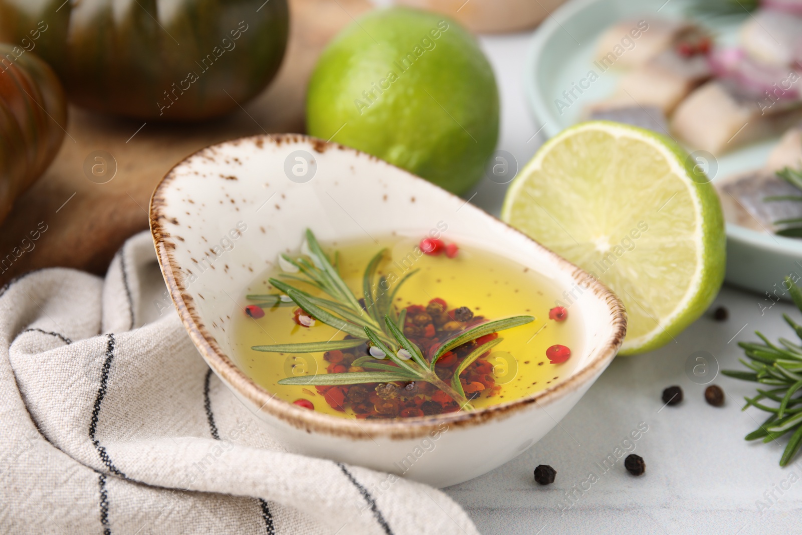 Photo of Tasty fish marinade with rosemary and products on light tiled table, closeup