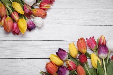 Beautiful colorful tulip flowers on white wooden table, flat lay. Space for text