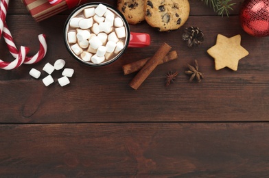 Photo of Flat lay composition with delicious marshmallow cocoa and Christmas decor on wooden table. Space for text