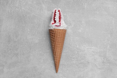 Photo of Delicious ice cream with raspberry jam in waffle cone on light gray background, top view