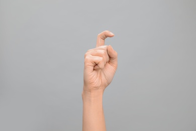 Photo of Woman showing X letter on grey background, closeup. Sign language