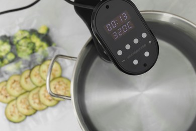 Photo of Sous vide cooker in pot on white table, closeup. Thermal immersion circulator