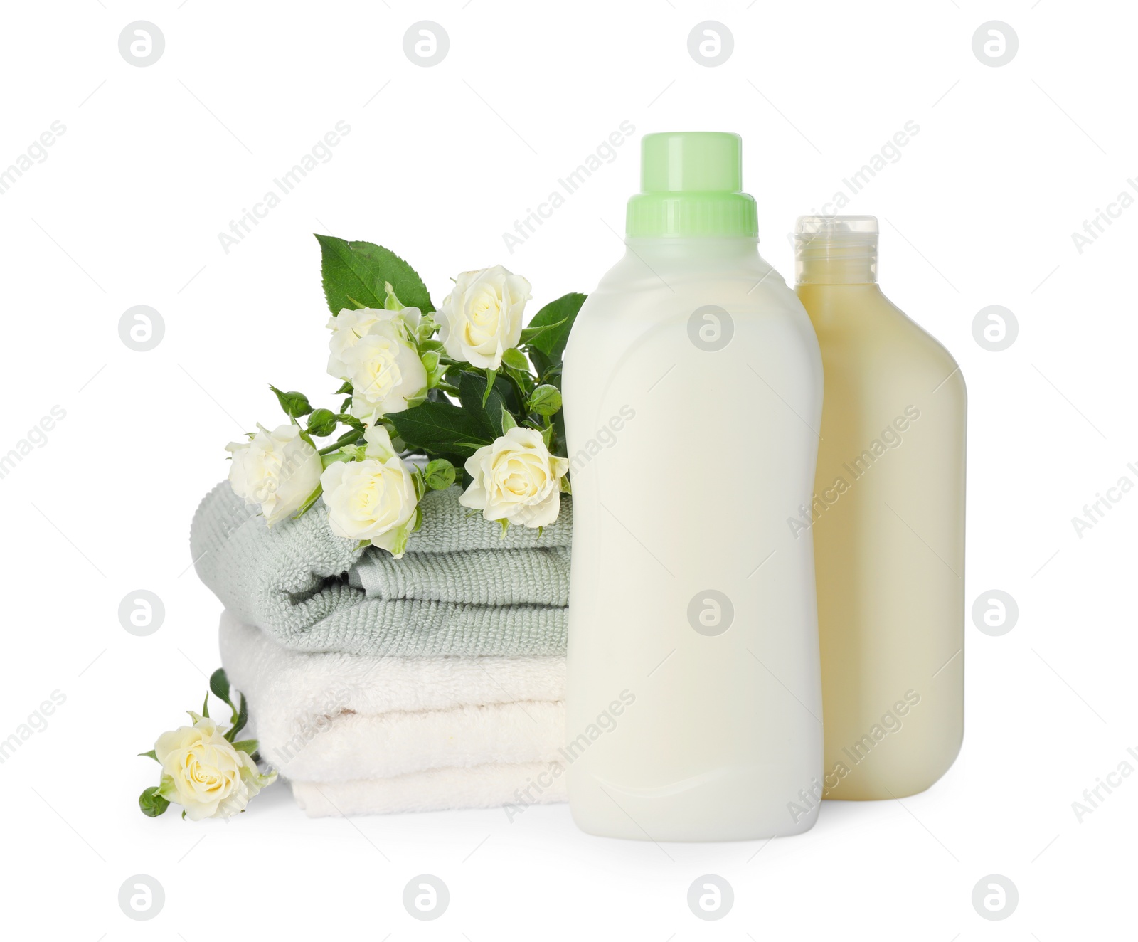 Photo of Bottles of fabric softener, stacked clean towels and beautiful flowers isolated on white