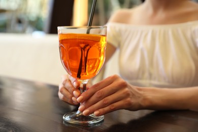 Young woman with Aperol spritz cocktail resting at restaurant, closeup