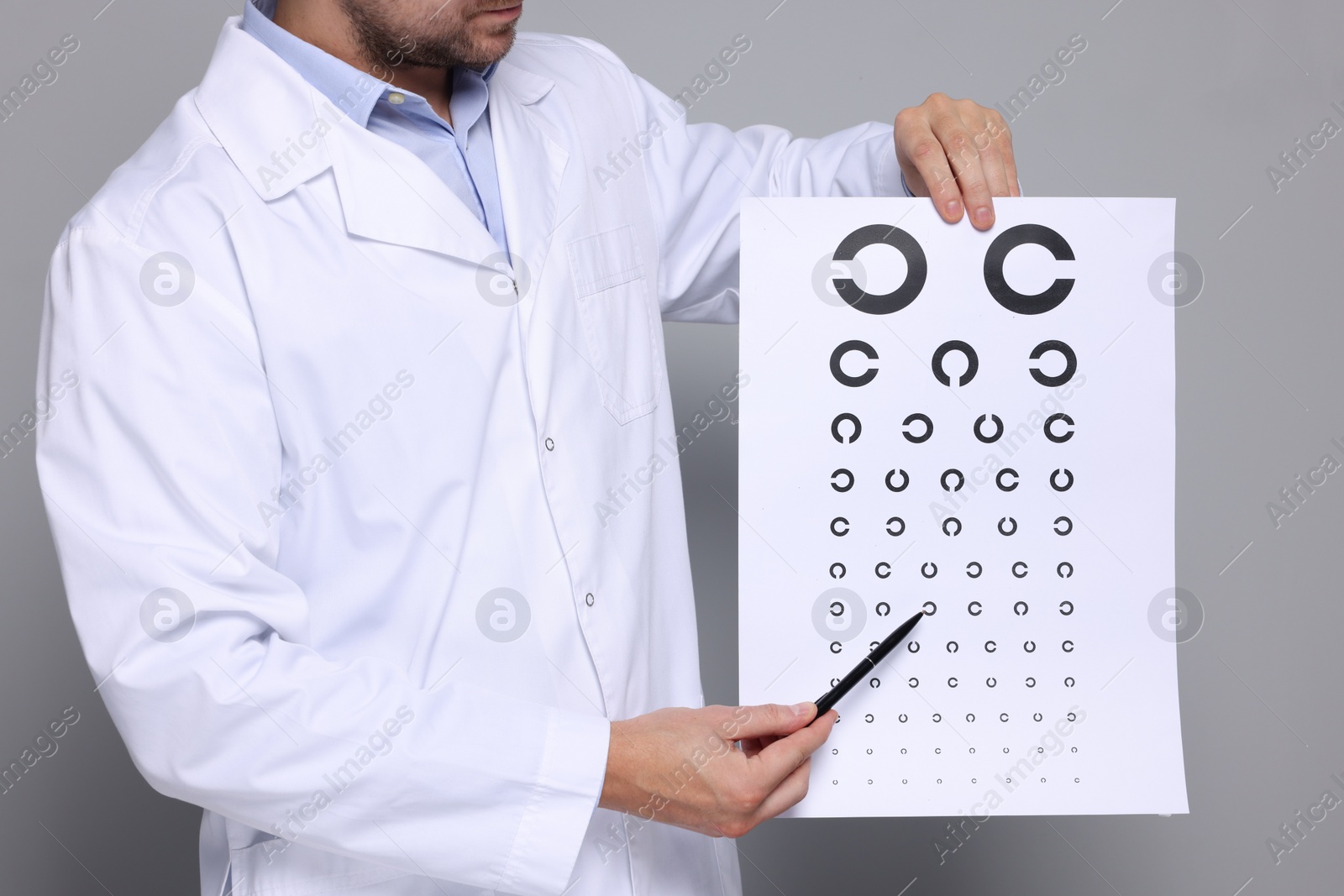 Photo of Ophthalmologist pointing at vision test chart on gray background, closeup