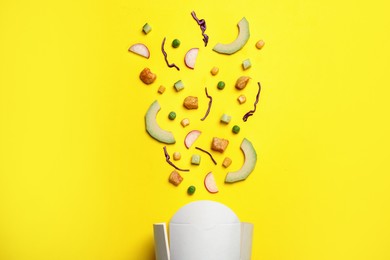 Photo of Flat lay composition with ingredients for salad and paper container on yellow background