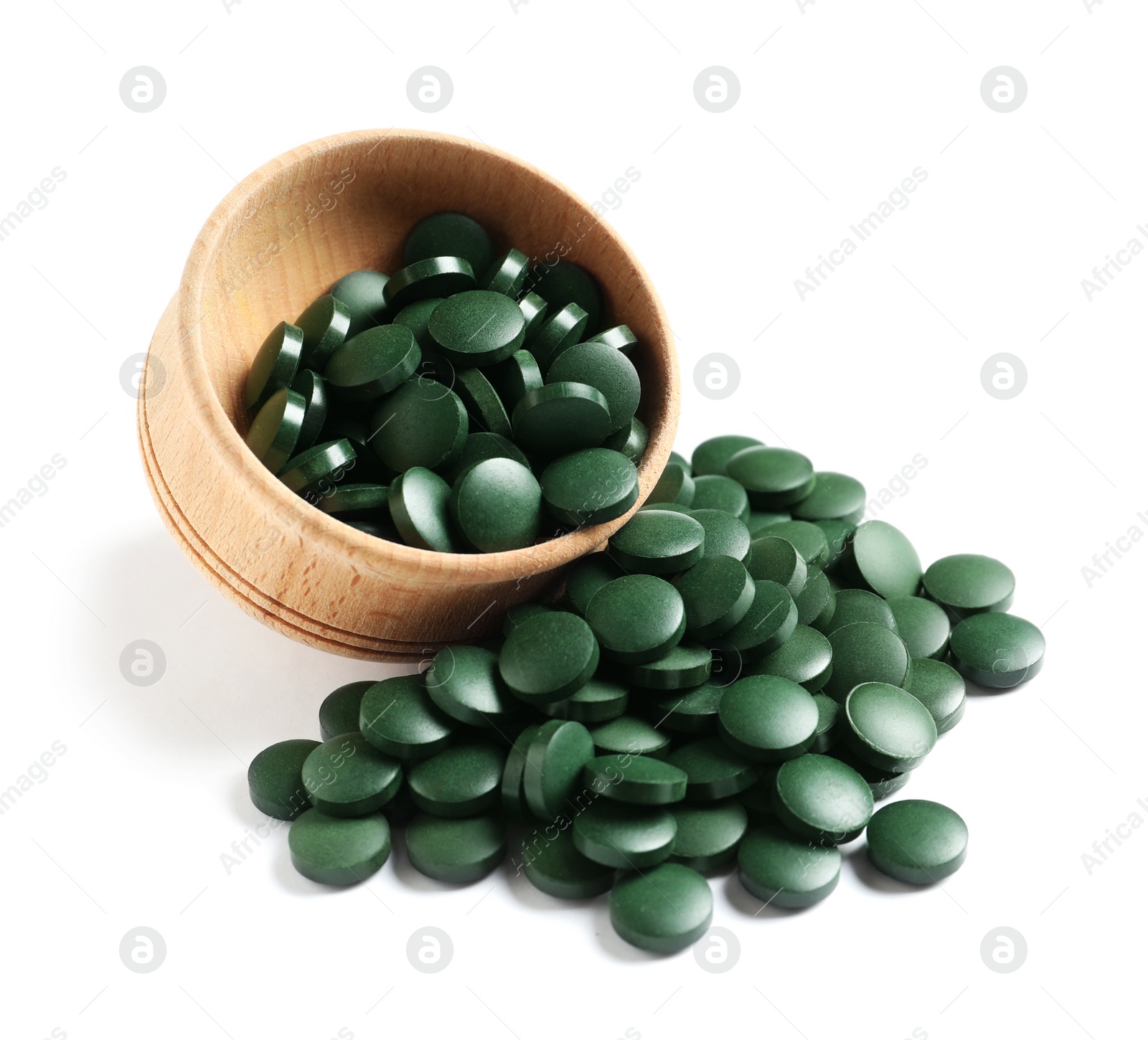 Photo of Wooden bowl with green spirulina pills on white background