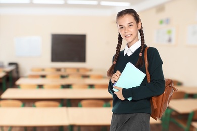 Teen girl with backpack in empty school classroom