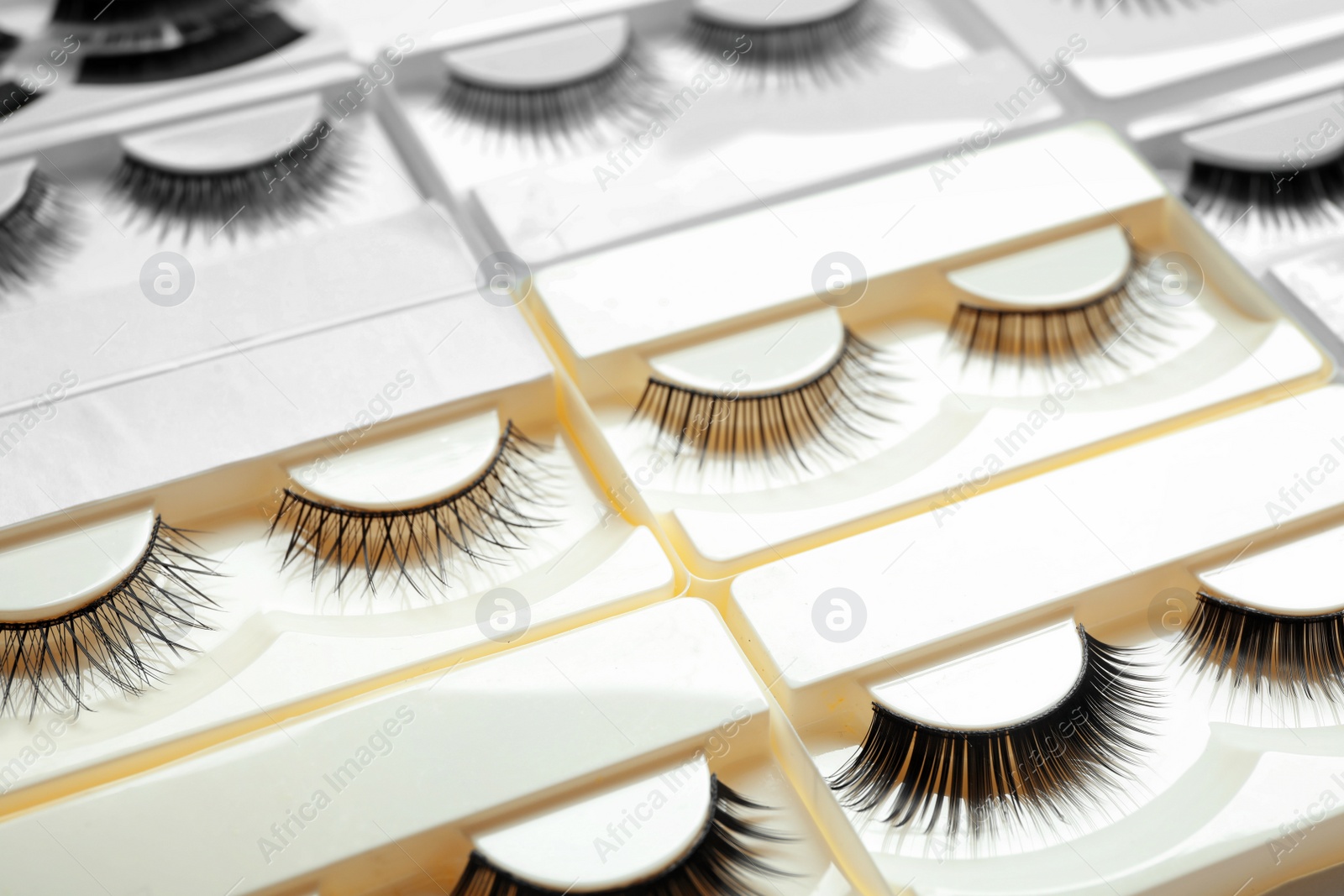 Photo of Set with different false eyelashes in packs as background, closeup