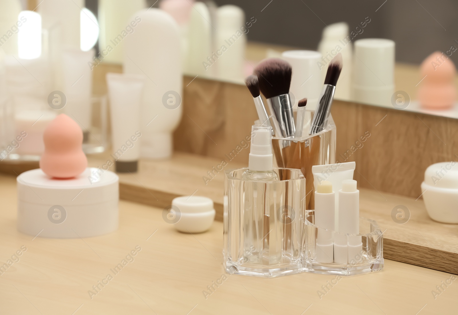 Photo of Organizer with cosmetic products and makeup accessories on dressing table indoors