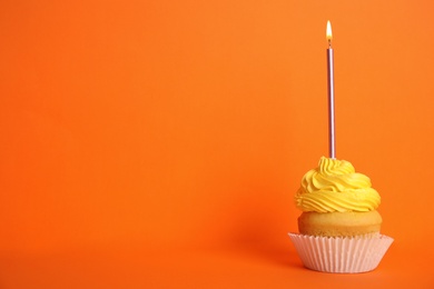 Birthday cupcake with candle on orange background, space for text