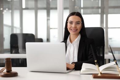 Photo of Smiling lawyer working on laptop in office