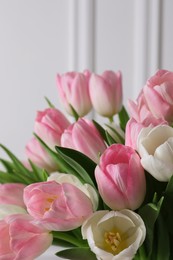 Photo of Beautiful bouquet of tulips against white wall, closeup