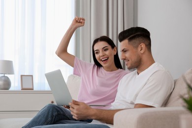 Photo of Emotional couple participating in online auction using laptop at home