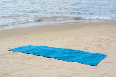 Blue towel on sandy beach near sea
