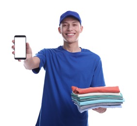 Photo of Dry-cleaning delivery. Happy courier holding folded clothes and smartphone on white background