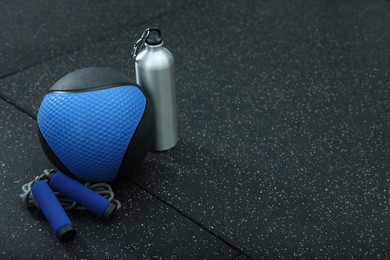 Photo of Blue medicine ball, bottle and skipping rope on floor, space for text