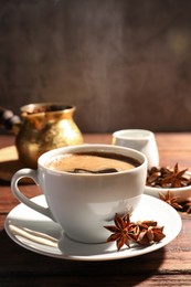 Photo of Cup of aromatic hot coffee with anise stars on wooden table