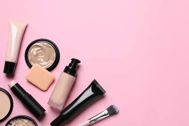 Liquid foundation, beauty accessories and face powders on pink background, flat lay. Space for text