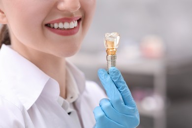 Dentist holding educational model of dental implant indoors, closeup. Space for text