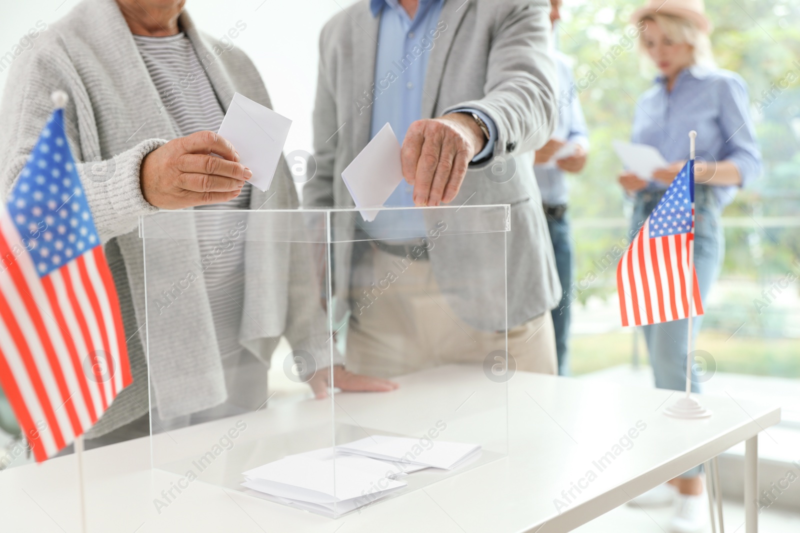 Photo of Elderly people putting ballot papers into box at polling station