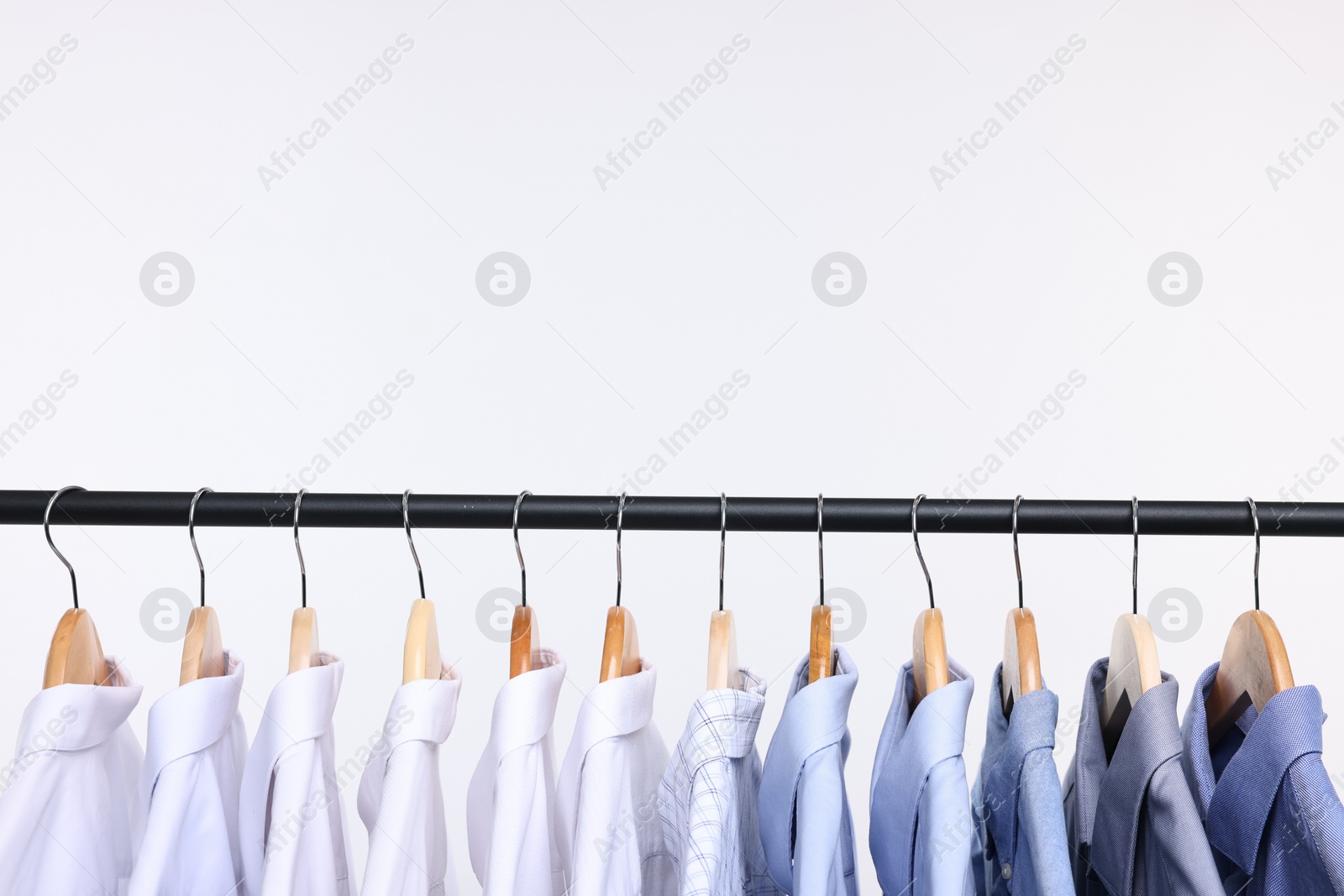 Photo of Dry-cleaning service. Many different clothes hanging on rack against white background, space copy text