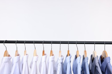 Photo of Dry-cleaning service. Many different clothes hanging on rack against white background, space copy text