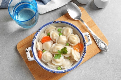 Photo of Bowl of dumplings in broth served on table, top view