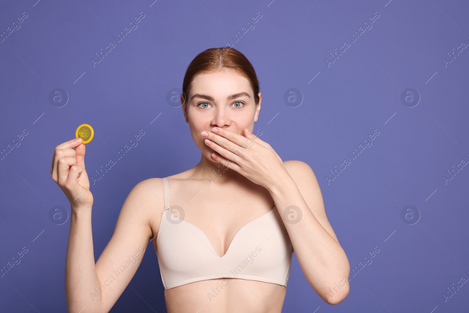 Photo of Woman in bra holding condom on purple background. Safe sex