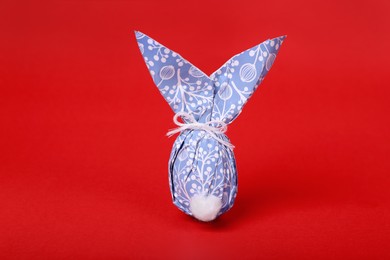 Easter bunny made of wrapping paper and egg on red background