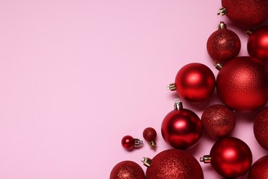 Shiny red Christmas balls on pink background, flat lay. Space for text