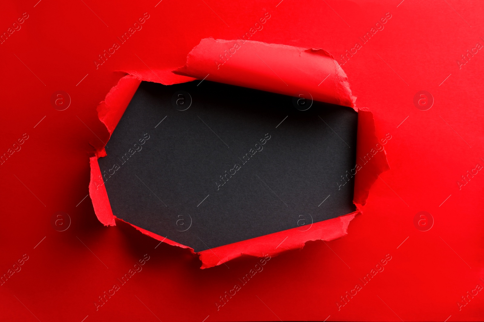 Photo of Hole in red paper on black background