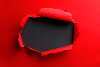 Hole in red paper on black background