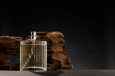 Luxury men`s perfume in bottle on grey table against dark background, space for text